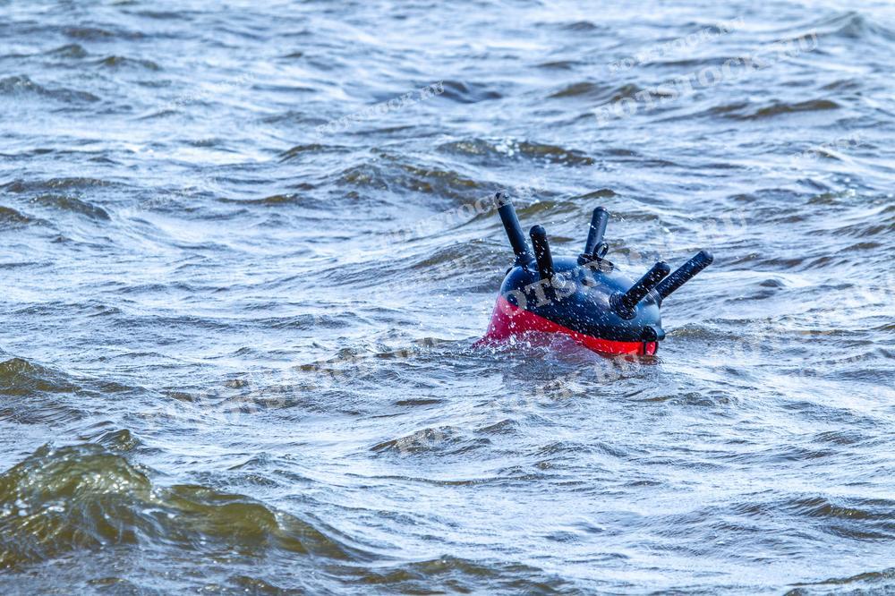 Фотография морской мины, плавающей на поверхности воды. Мина оборудована шипами и частично окрашена в красный цвет, что подчеркивает её опасное предназначение в оборонительных операциях.